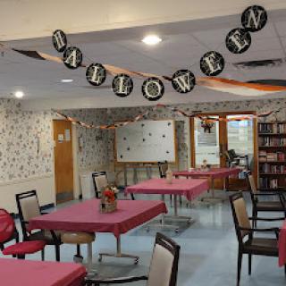 A decorated dining area ready for a Halloween celebration, featuring festive banners and set tables.