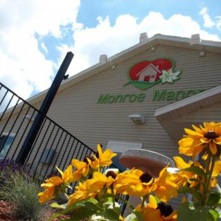 A sunny day at a building adorned with bright yellow flowers and a visible sign.