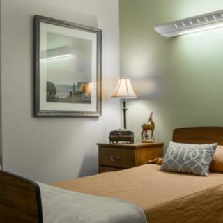 A cozy bedroom with a neatly made bed, a bedside table, and decorative elements like a lamp and artwork on the wall.