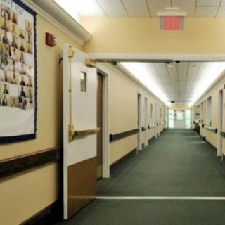 A long, illuminated hallway with doors on either side and a carpeted floor.