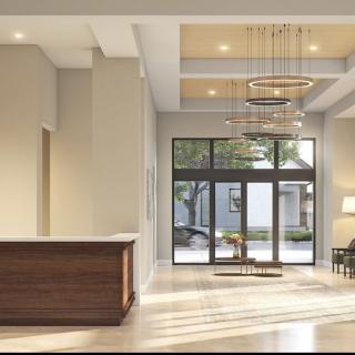 A modern and minimalist lobby with a reception desk, chandeliers, and large windows.