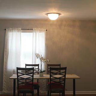 A minimalist dining room setup with a table and chairs by a window.