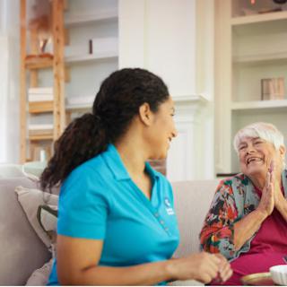 A caregiver enjoying a heartfelt conversation with an elderly woman in a cozy home setting.