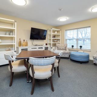 A modern living room with a dining table, chairs, and a television mounted on the wall.
