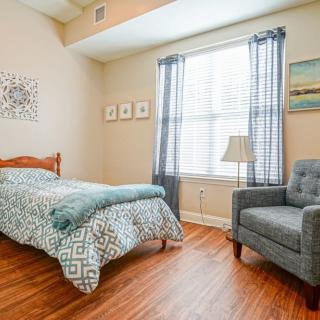 A cozy bedroom with a single bed, armchair, and natural light coming through the window.