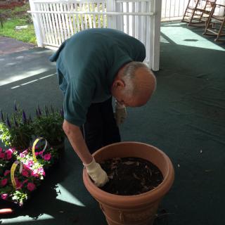 A person engaged in gardening, planting something in a large pot outdoors.