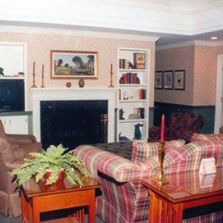 A cozy living room with a fireplace, sofas, and a bookshelf filled with decor.
