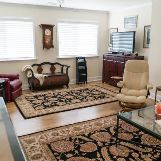 A cozy living room featuring classic furniture, patterned rugs, and natural lighting from large windows.