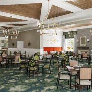 A spacious and modern dining room with elegant chandeliers, tables, and chairs arranged neatly.