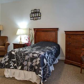 A cozy bedroom with a single bed, nightstand, and warm lighting.