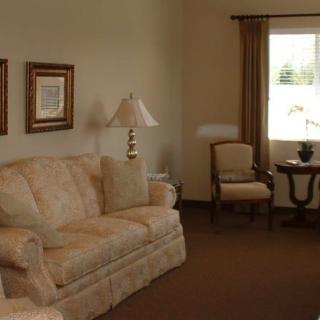 A cozy living room with a sofa, lamp, and window overlooking the outside.