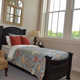 A cozy bedroom with a single bed and large windows.