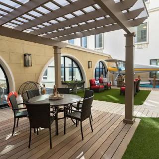 A stylish courtyard patio with a pergola, featuring comfortable outdoor furniture and a well-maintained lawn.