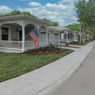 A row of suburban houses with front porches and an American flag displayed.