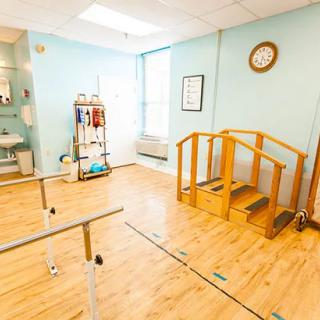 A physical therapy room equipped with parallel bars and a small staircase for rehabilitation exercises.
