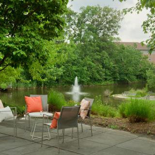 A serene outdoor seating area by a tranquil fountain, surrounded by lush greenery.