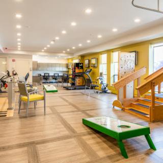 A well-lit and spacious fitness center equipped with various exercise machines and recreational activities.