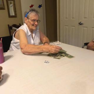 An elderly woman playing cards at a table indoors.