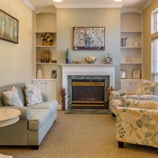 A cozy living room with a fireplace, sofas, and decorative shelves.