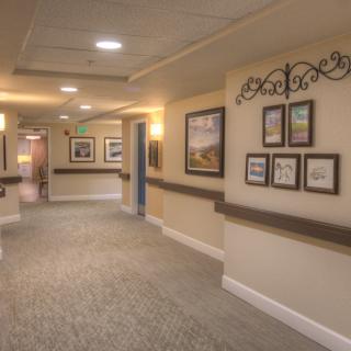 A well-lit hallway featuring artwork on the walls and a carpeted floor.