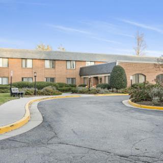 A view of a brick building set in an urban landscape, featuring a winding roadway and surrounding greenery.