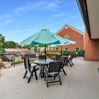 A cozy outdoor patio area featuring tables and chairs shaded by a large umbrella, perfect for relaxation.