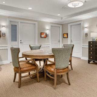 A cozy dining area with a round wooden table surrounded by four chairs, elegant lighting, and tasteful decor.