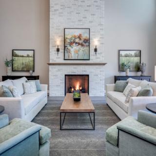 A modern living room with a central fireplace, comfortable sofas, and elegant artwork.