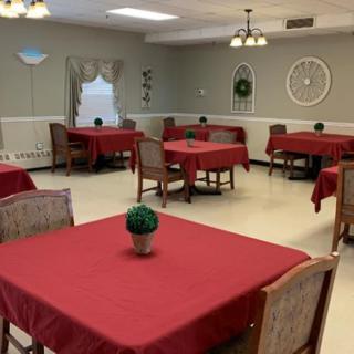 A cozy dining room with tables covered in red tablecloths and simple decoration.