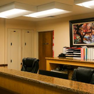 A well-organized office reception area featuring a desk, chairs, and decorative artwork.
