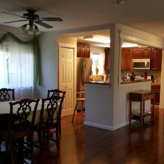 A view of a spacious kitchen and dining area with wooden flooring and classic furniture.