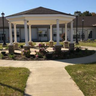 A beautiful garden gazebo with columns surrounded by a well-maintained landscape.