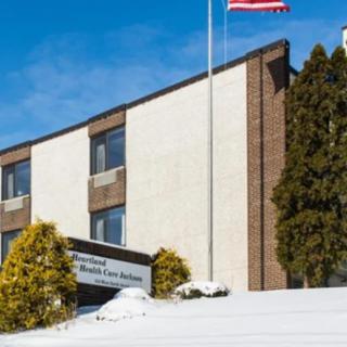 A winter scene featuring a building with an American flag, surrounded by snow and evergreen trees.