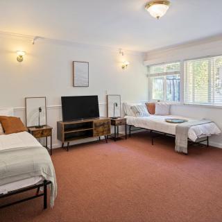 A spacious bedroom with two beds, a television, and ample natural light.