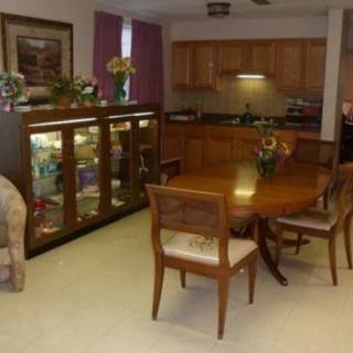 A cozy dining room with wooden furniture and a kitchen in the background.