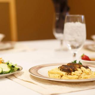 A gourmet meal is elegantly served on a dining table, featuring pasta with creamy sauce and a side salad.