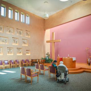 An interior view of a church featuring a prominent cross and seating arrangements for worshippers.