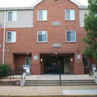 Front view of a brick residential building with stairs leading to the entrance.