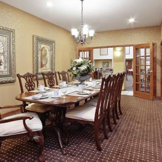 A spacious dining room with an elegant wooden table set for a meal, surrounded by matching chairs and adorned with a central chandelier.