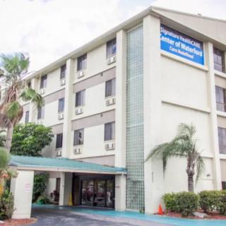 The exterior view of a hotel building with palm trees at the entrance.