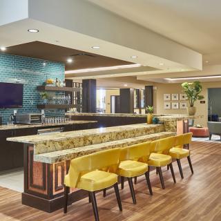 A modern kitchen with a spacious island counter and vibrant yellow stools.