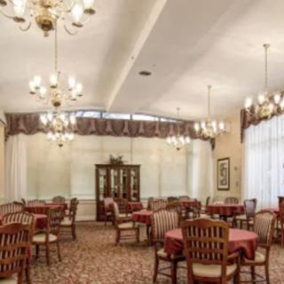 An elegant dining room with neatly arranged tables and chairs, featuring chandeliers and traditional decor.