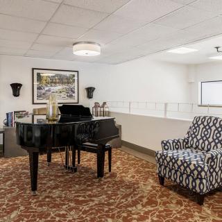 A cozy interior space featuring a grand piano, patterned armchair, and elegant decor.