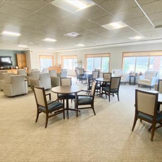 A spacious dining area with multiple tables and chairs, well-lit by natural and artificial lighting.