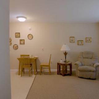 A cozy living area featuring a simple table and chairs, a comfortable armchair, and decorative wall art.