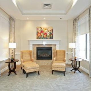 A elegantly decorated living room featuring two chairs and a fireplace, adorned with a painting and surrounded by soft lighting.