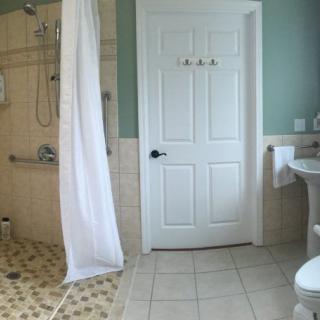 A modern bathroom featuring a shower with a curtain, tiled floor, and a sink.