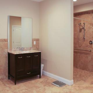 A modern bathroom featuring a dark vanity with a mirror and a spacious shower area.