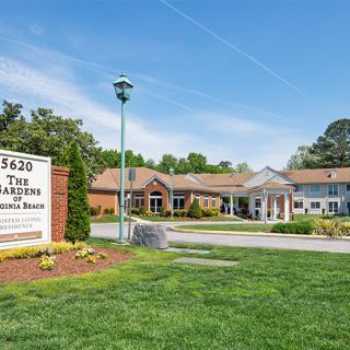 A building with a sign in front, surrounded by green grass and clear blue sky.