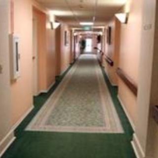 A long hallway with a patterned carpet and wall-mounted lights.